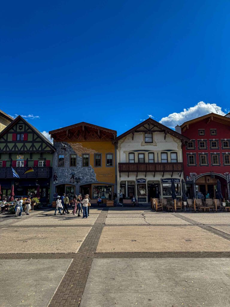 Colorful Bavarian-style buildings and visitors walking through the town square in Leavenworth, Washington, on a sunny day.