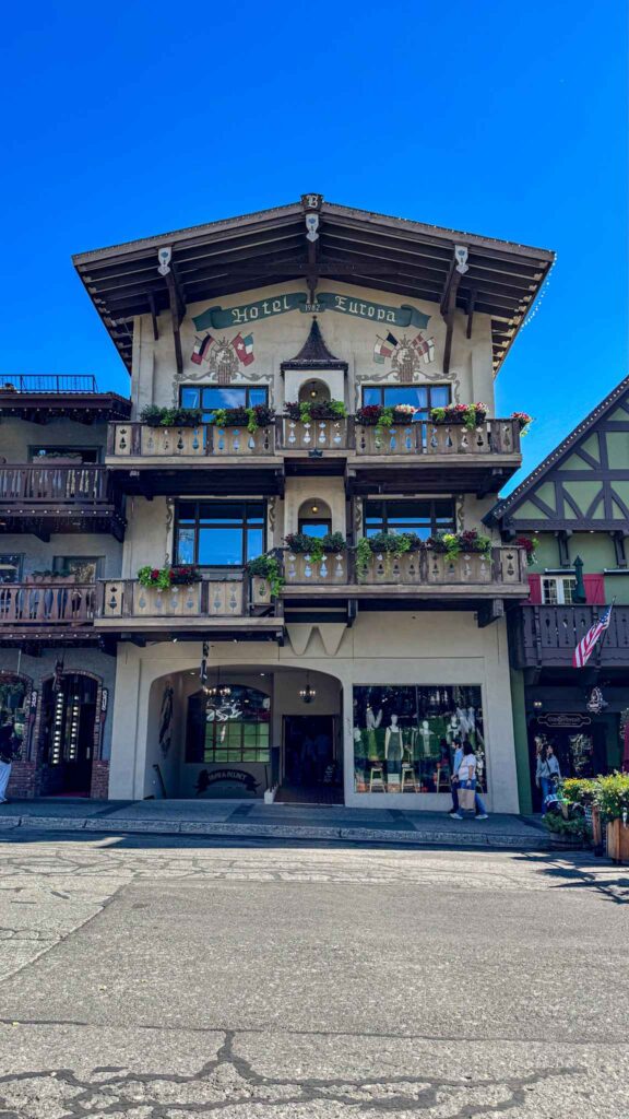Bavarian-style Hotel Europa building in downtown Leavenworth, Washington, with wooden balconies and flower boxes under a clear blue sky.