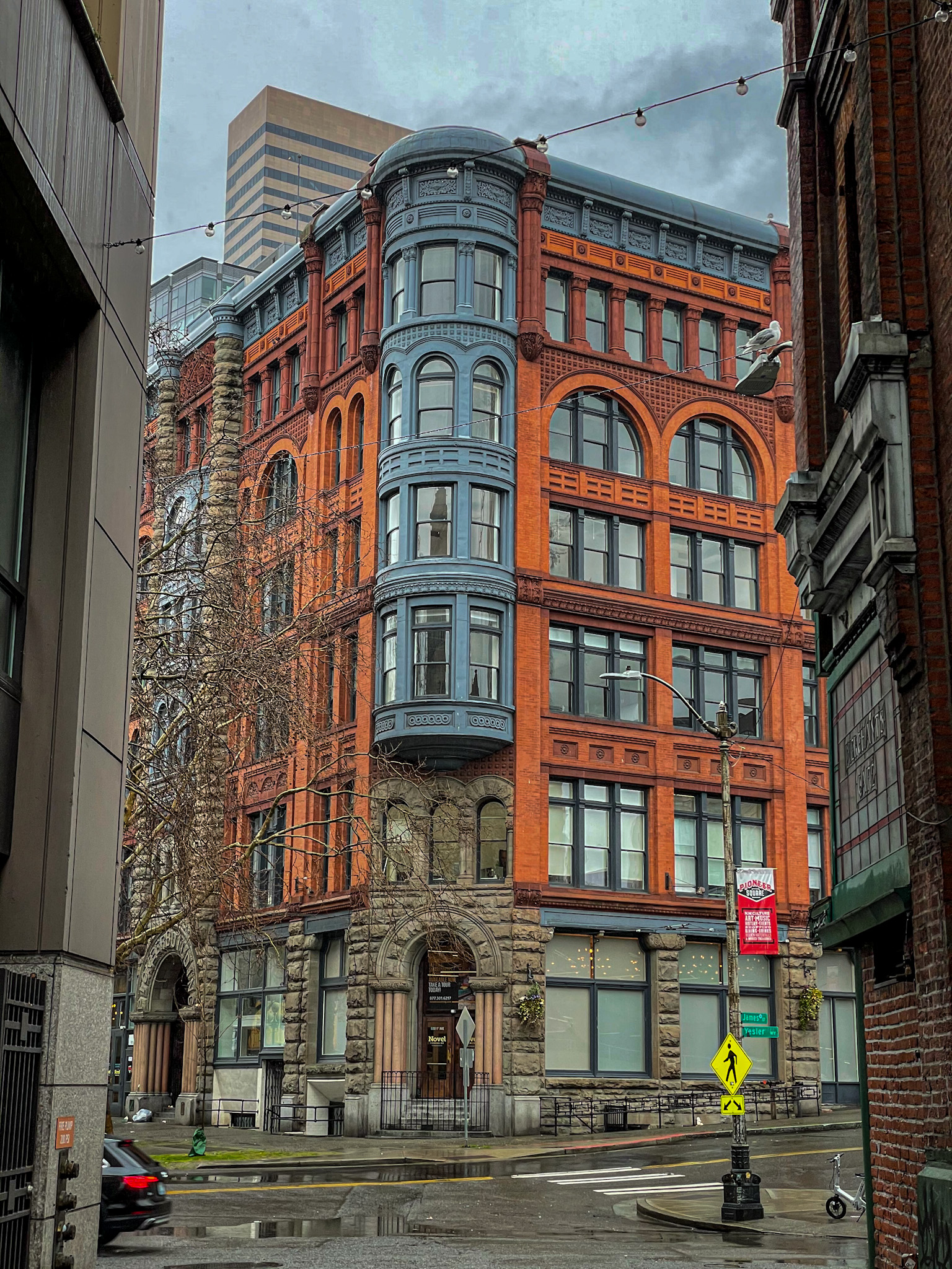 Historic red brick Romanesque-style building in Pioneer Square neighborhood of Seattle on a rainy day.
