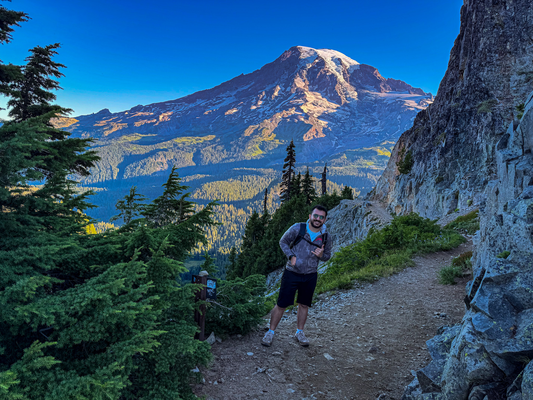 Hiker on a mountain trail with Mount Rainier in the background in Mount Rainier National Park.
