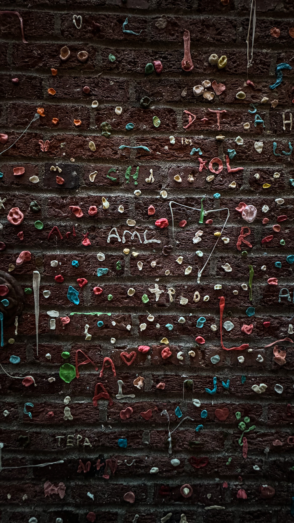 Colorful chewing gum covering a brick wall at the famous Gum Wall in Seattle near Pike Place Market.
