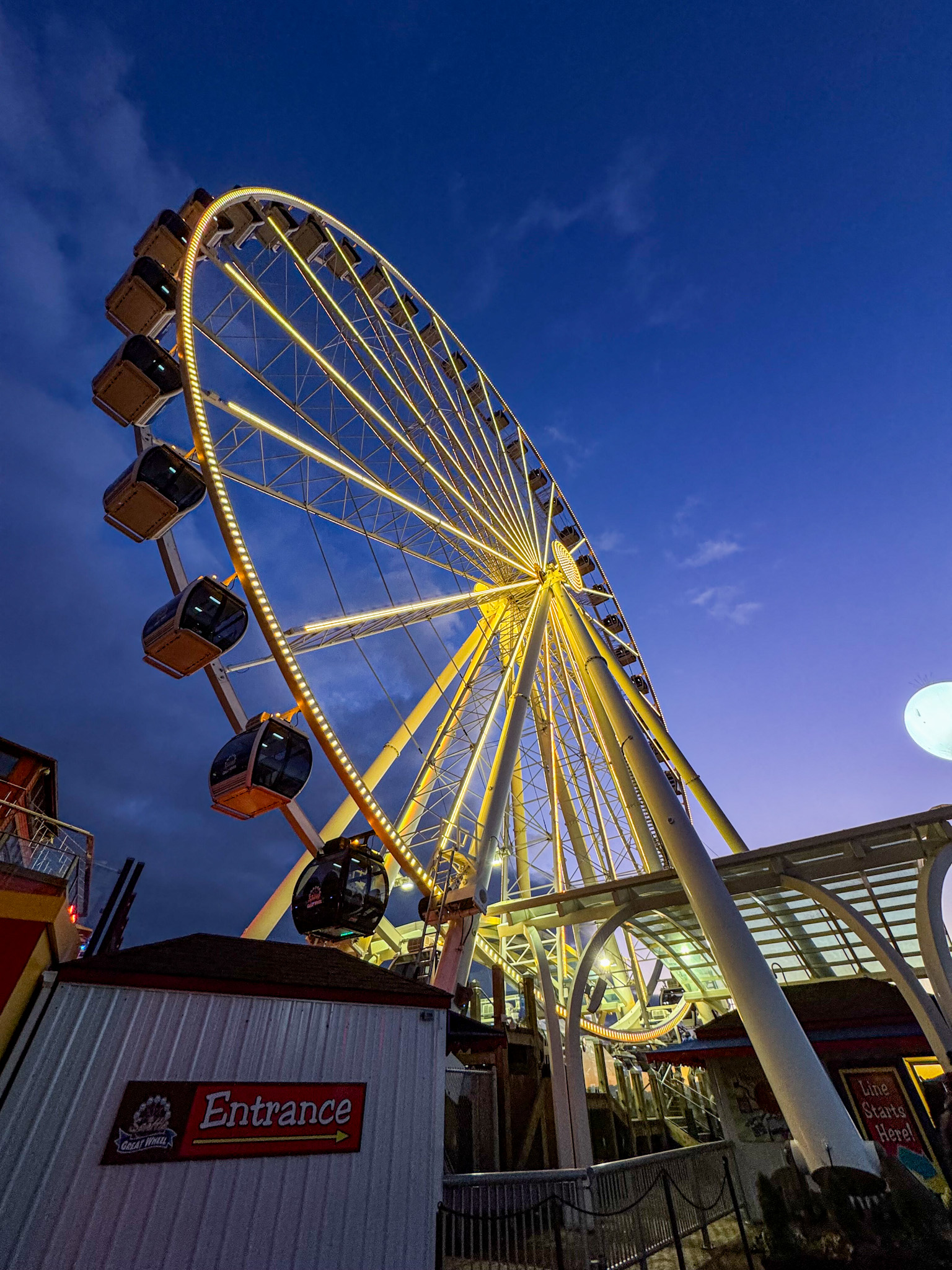 Seattle Great Wheel glowing at night along the waterfront with blue evening sky.
