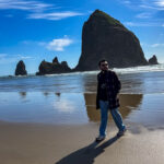 Person walking on Cannon Beach with Haystack Rock in the background on the Oregon Coast.