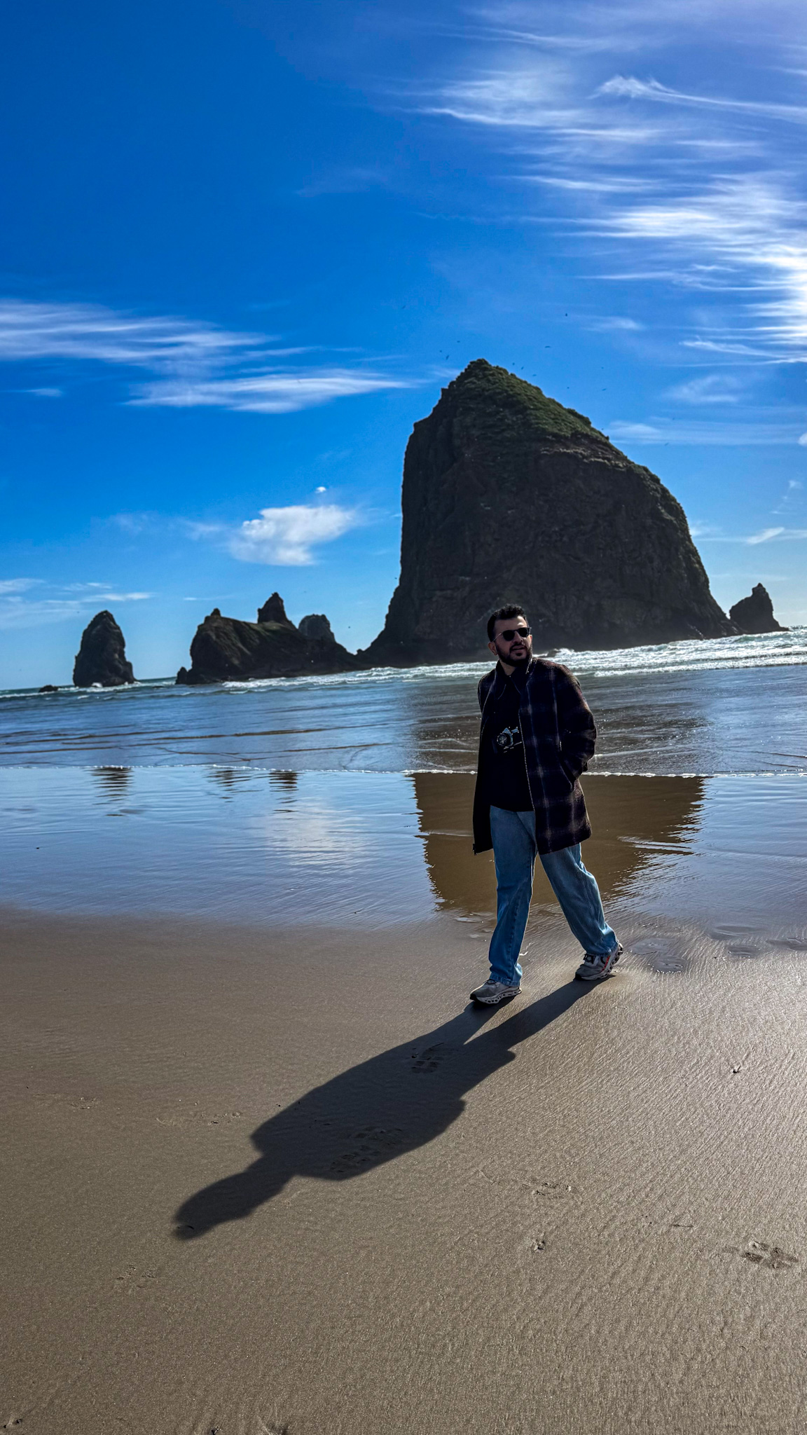 Person walking on Cannon Beach with Haystack Rock in the background on the Oregon Coast.
