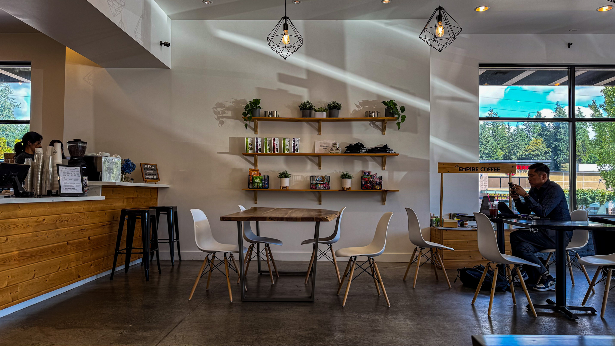 Minimalist coffee shop interior with wooden counter, white chairs, and natural light in Seattle.
