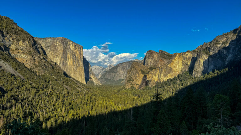Panoramic view of Yosemite Valley from Tunnel View showing El Capitan, Bridalveil Fall, and forest below.