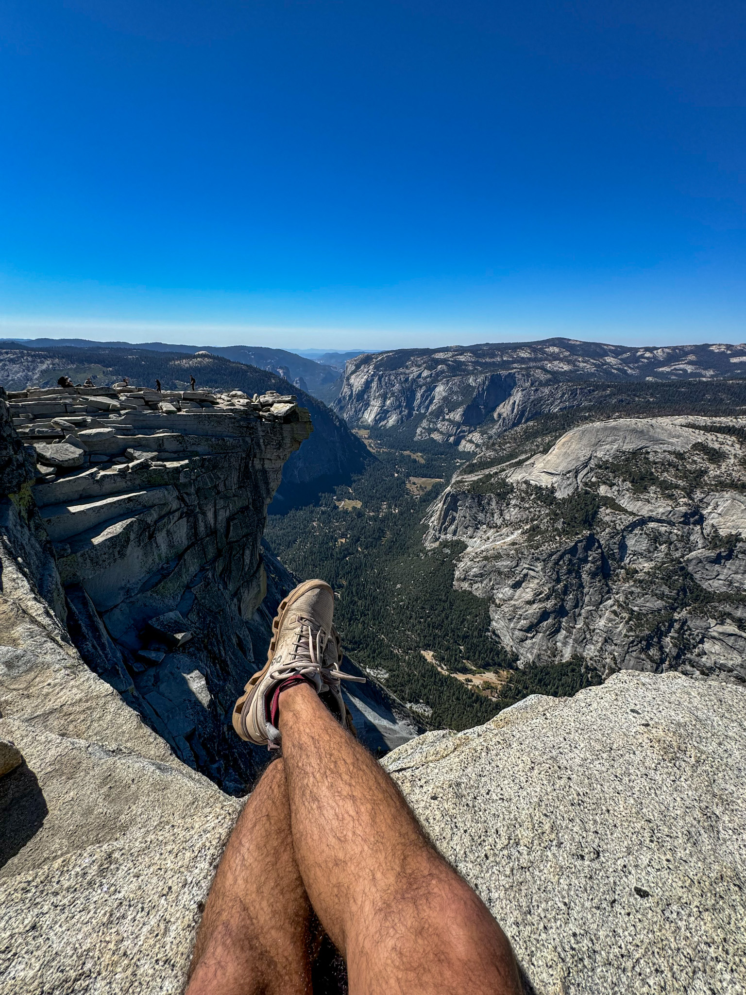 View from the top of Half Dome in Yosemite National Park overlooking Yosemite Valley and granite cliffs.