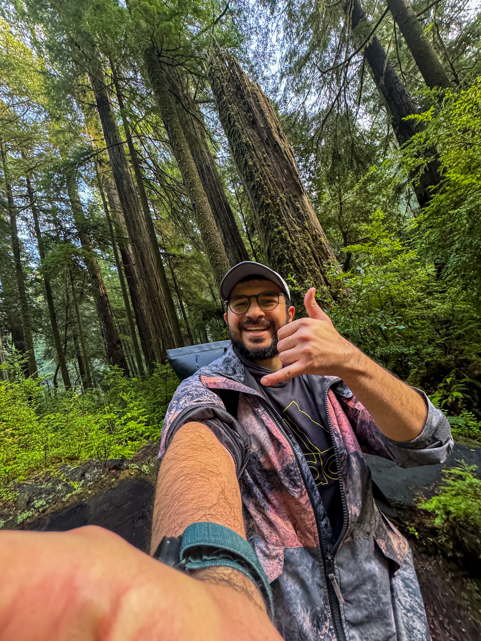 Traveler taking a selfie while hiking among towering redwood trees in Redwood National and State Parks in California.
