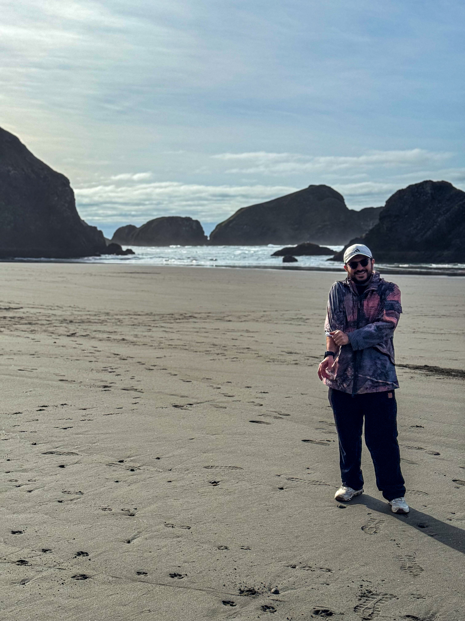 Wide sandy beach on the Oregon Coast with sea stacks in the Pacific Ocean.
