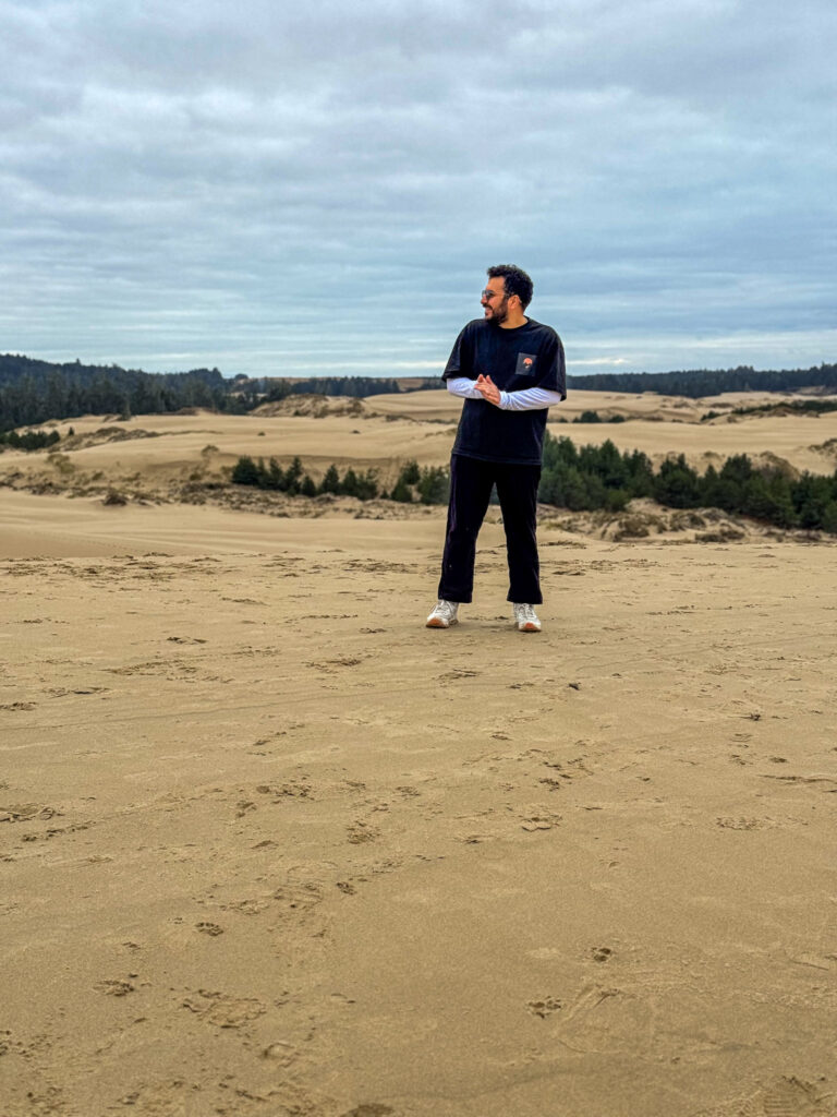 Traveler standing on large sand dunes at the Oregon Dunes National Recreation Area on the Oregon Coast.