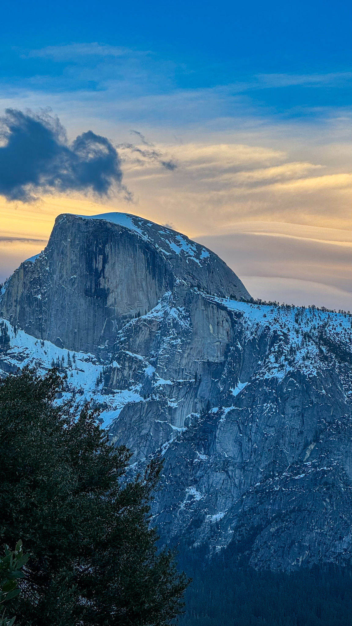 Half Dome in Yosemite National Park during sunset with snow-covered granite and colorful sky.