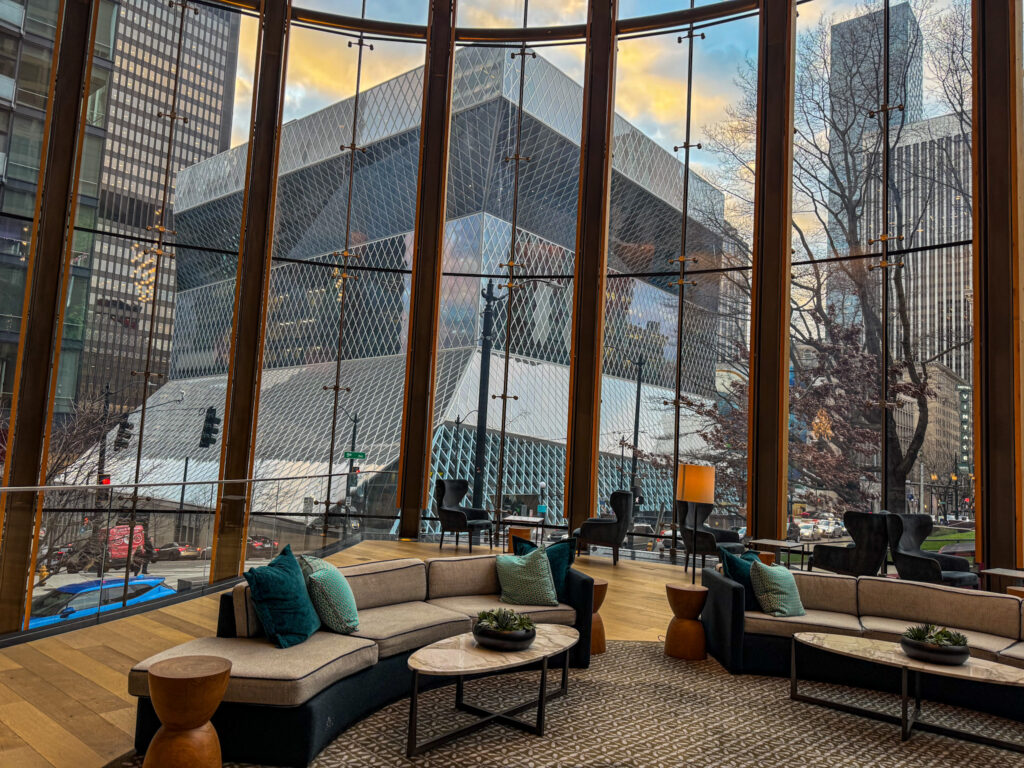 Modern lounge seating inside a glass-walled building with a view of the Seattle Central Library across the street.