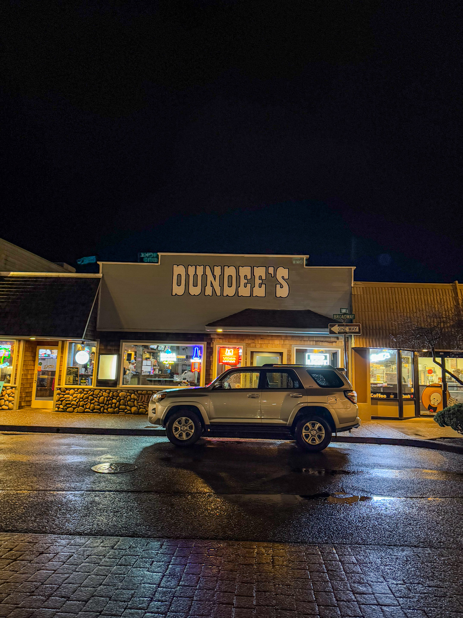 Dundee’s restaurant on Broadway street in Seaside Oregon at night with lights and parked car.