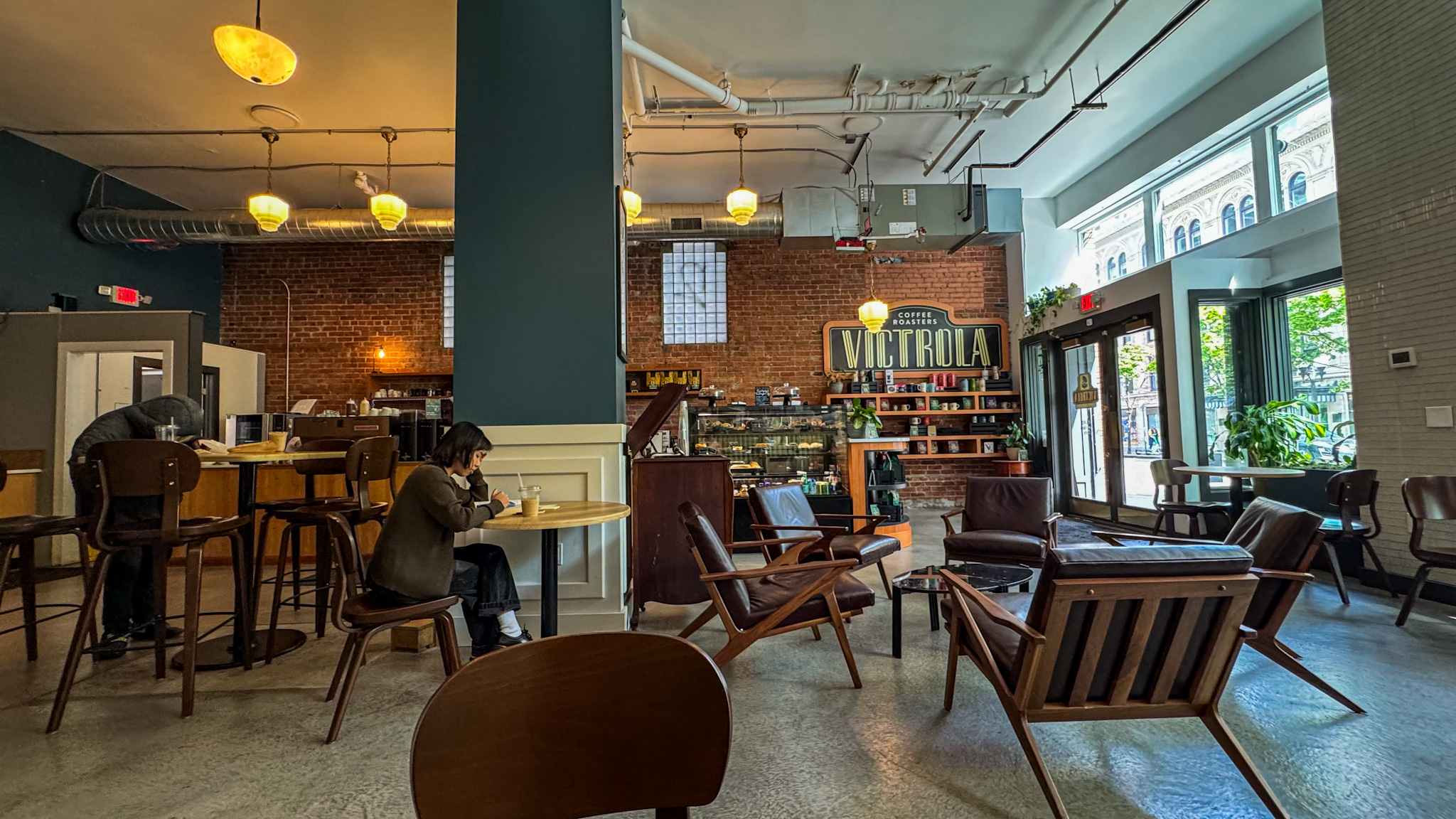 Interior of Victrola Coffee Roasters in Seattle with brick walls, wooden seating, and cozy lighting.
