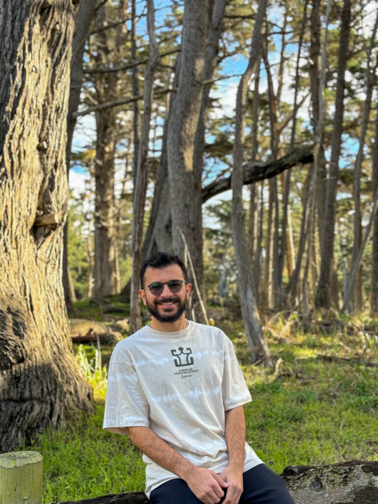 Traveler sitting on a log in a peaceful forest along the California coast.
