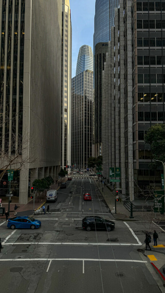 Downtown San Francisco street surrounded by tall skyscrapers and city traffic.