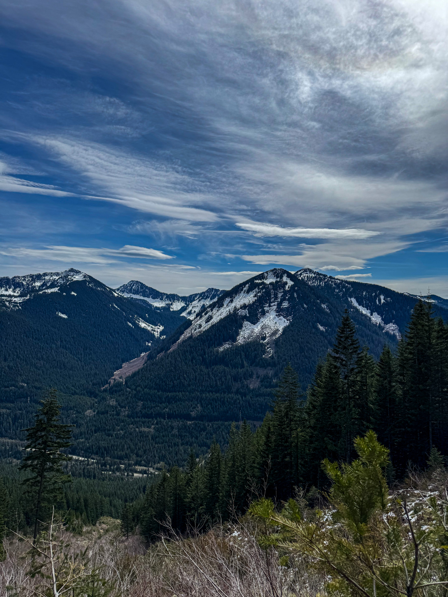 Snow-covered mountains and evergreen forests viewed from Granite Mountain Trail in Washington State.