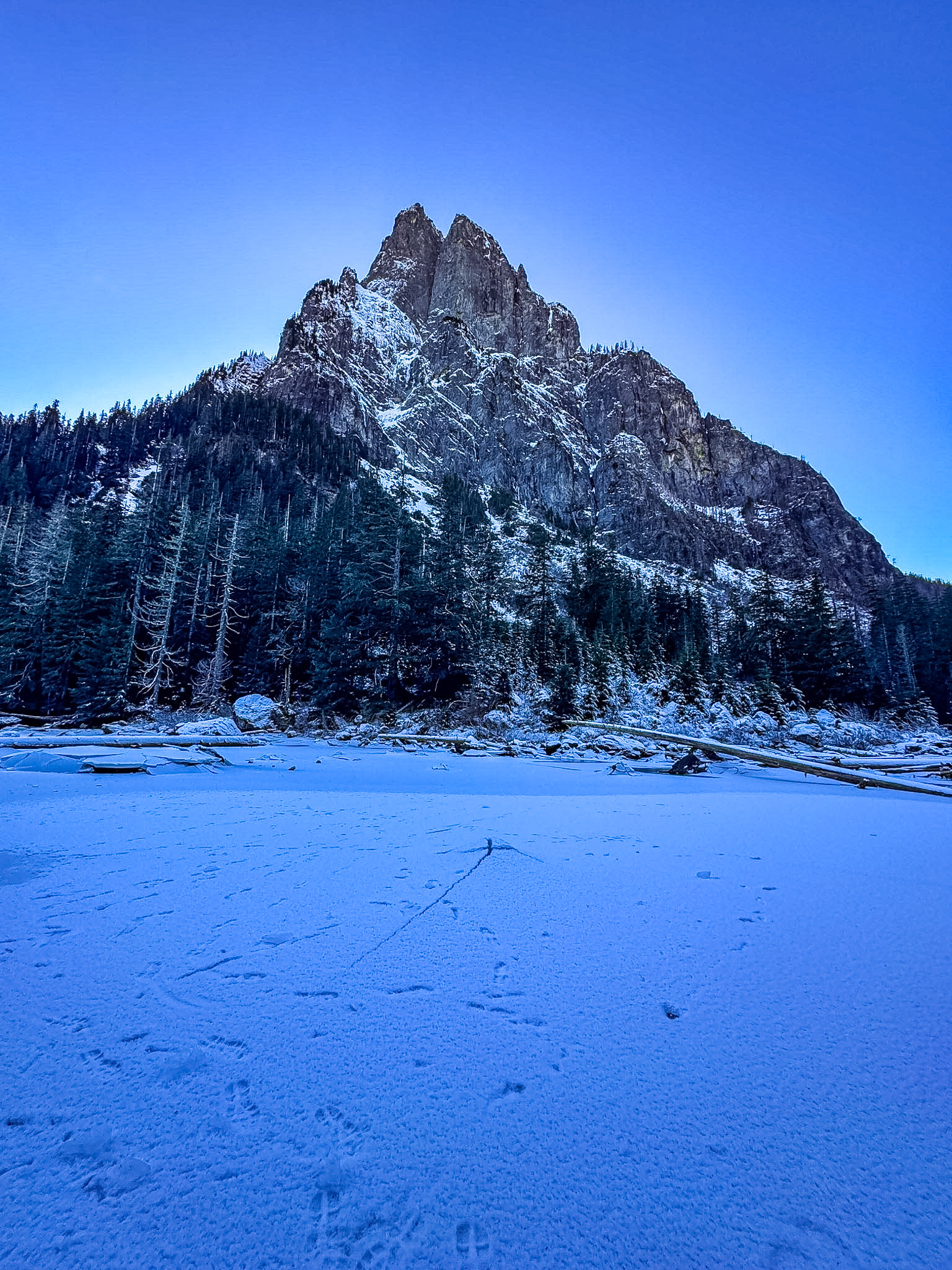 Frozen Barclay Lake surrounded by snowy mountains and pine trees in Washington.
