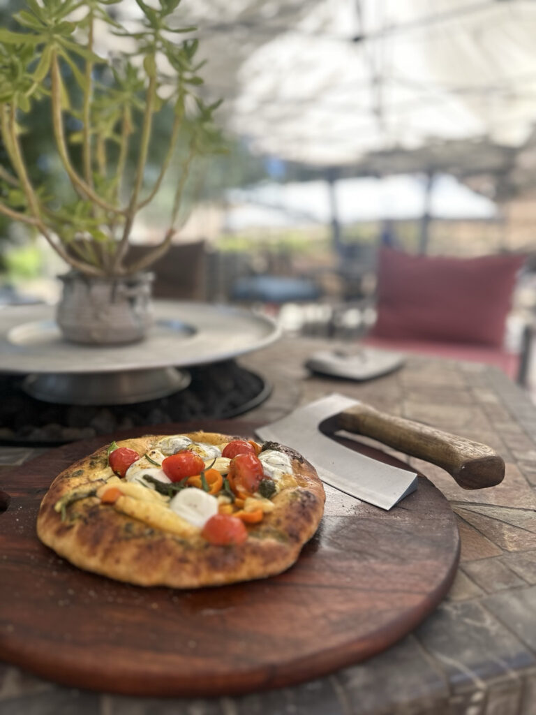 Fresh wood-fired pizza served at a Harvest Hosts farm with homemade ingredients and outdoor seating.