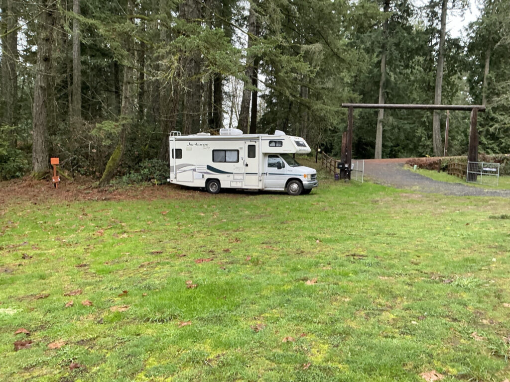 Class C RV parked overnight at a lavender farm through Harvest Hosts in Washington surrounded by open grass and evergreen trees.
