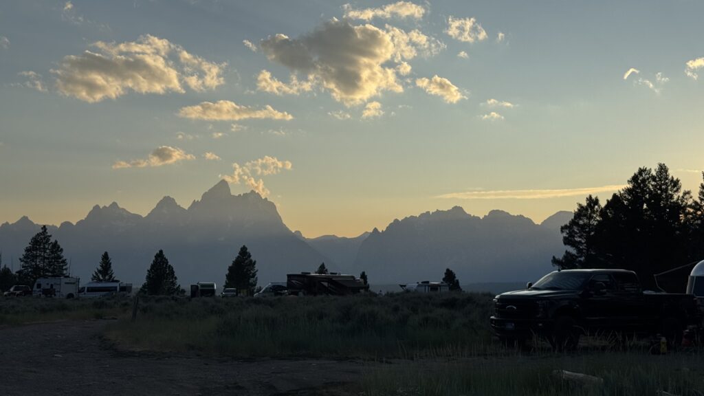 Sunset over Grand Teton National Park viewed from an RV campground with the Teton Range silhouetted against the evening sky.