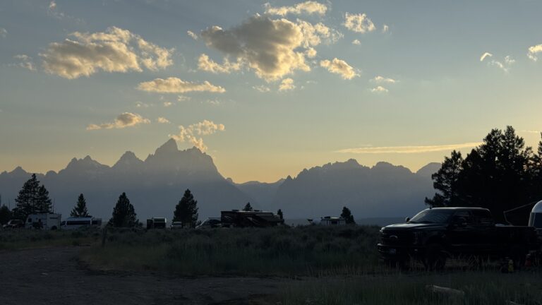 Sunset over Grand Teton National Park viewed from an RV campground with the Teton Range silhouetted against the evening sky.